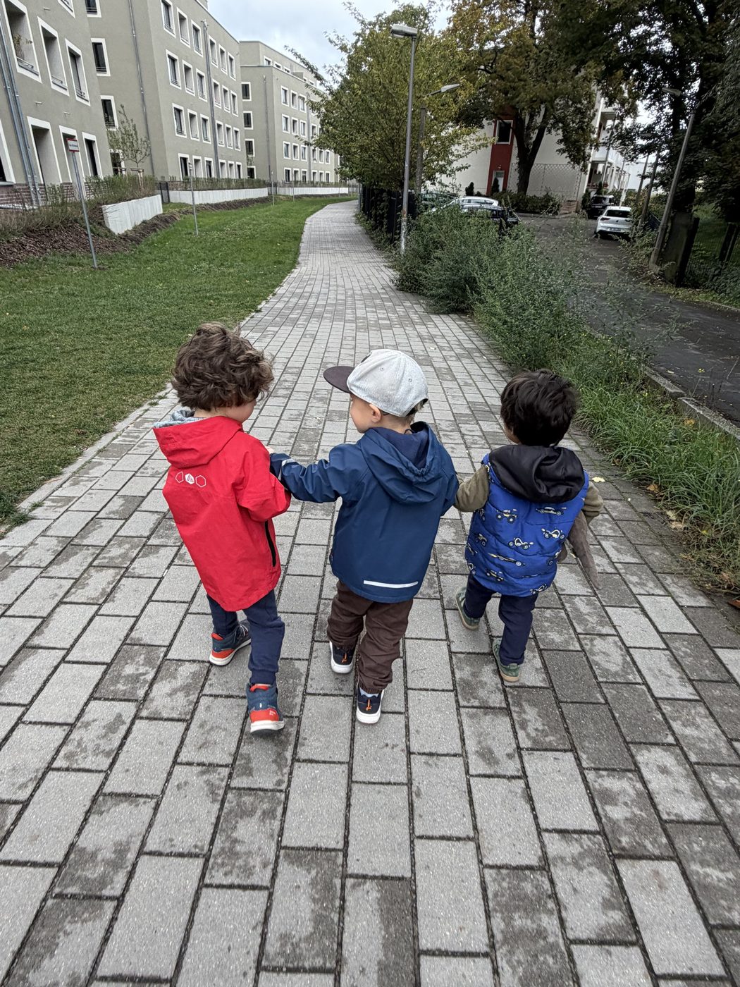 Drei Kinder gehen Hand in Hand einen Weg entlang
